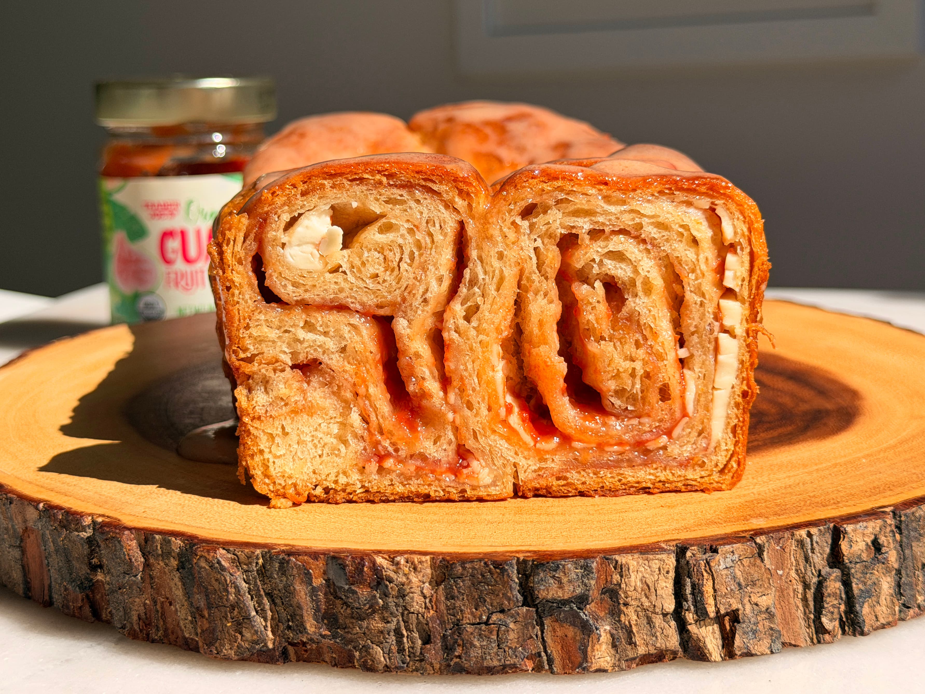 A golden loaf of guava cream cheese crescent bread with a pink guava glaze