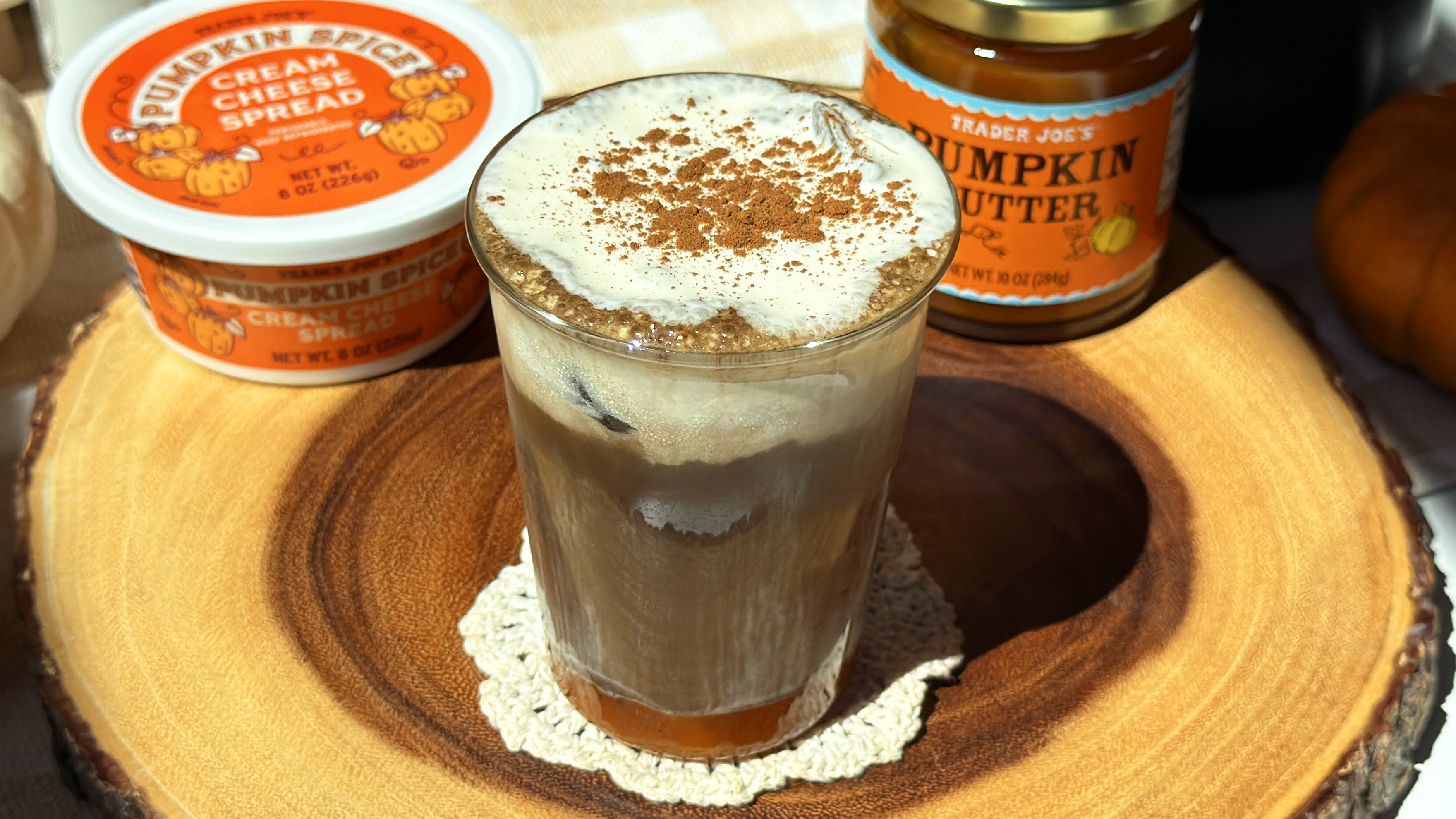Iced pumpkin spice hojicha latte dusted with pumpkin spice, between Trader Joe's pumpkin spice cream cheese spread and pumpkin butter